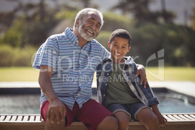 Smiling grandfather and grandson sitting together on bench