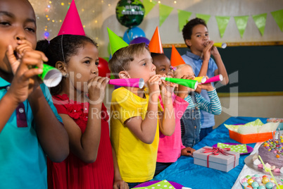 Playful kids blowing party horns