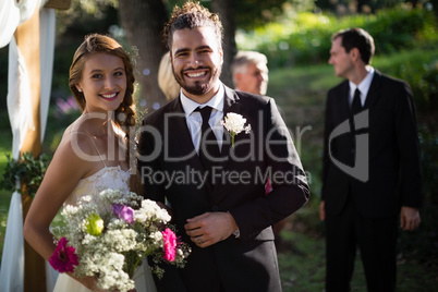 Happy bride and groom standing in park