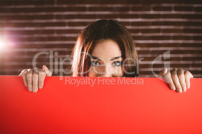 Portrait of smiling woman hiding face from blank sheet