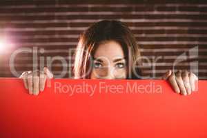 Portrait of smiling woman hiding face from blank sheet