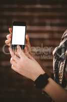 Woman showing mobile phone against brick wall