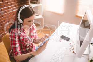 Smiling executive listening music on digital tablet