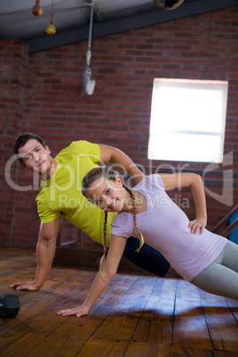 Trainer and teenage girl exercising in gym