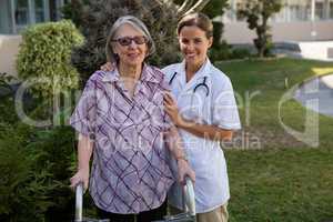 Doctor assisting woman in walking at backyard