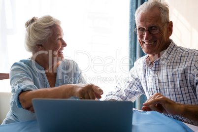 Friends laughing while looking at laptop