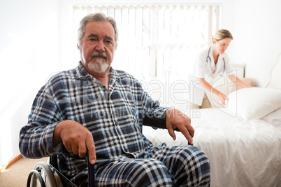 Portrait of senior man sitting on wheelchair while doctor working