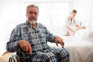 Portrait of senior man sitting on wheelchair while doctor working