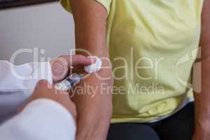 Physiotherapist injecting senior patient