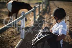 Boy holding horse saddle