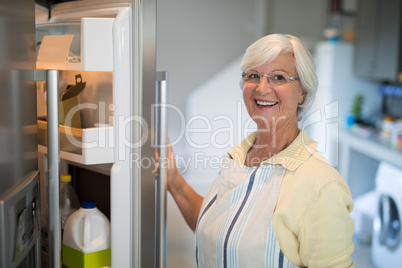 Smiling senior women opening the fridge