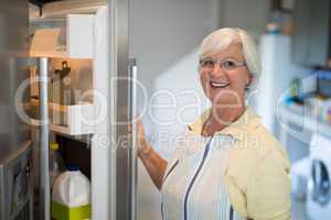 Smiling senior women opening the fridge