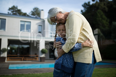 Grandmother and granddaughter embracing each other in garden