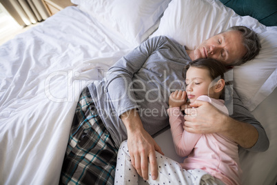 Father and daughter sleeping together on bed in bedroom