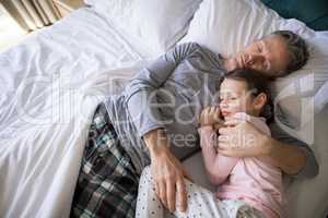 Father and daughter sleeping together on bed in bedroom