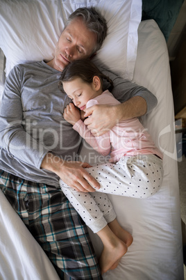 Father and daughter sleeping together on bed in bedroom