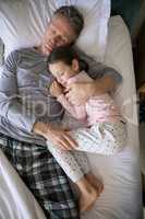 Father and daughter sleeping together on bed in bedroom