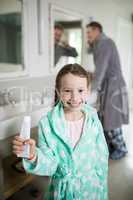 Smiling girl holding toothpaste in bathroom