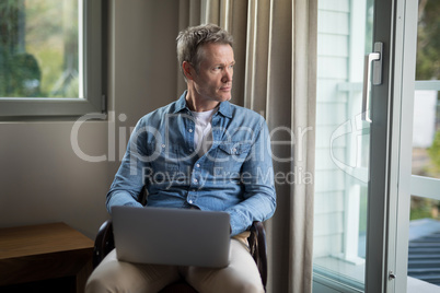 Thoughtful man using laptop on chair Thoughtful man using laptop on chair