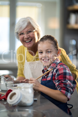 Granddaughter and grandmother posing while standing in the kitchen