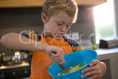 Boy mixing batter in blue container