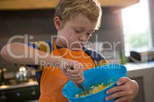 Boy mixing batter in blue container