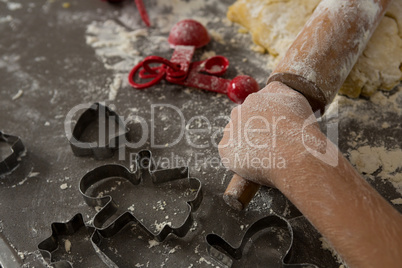 Cropped hand of boy rolling dough