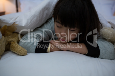 Girl with toys resting on bed