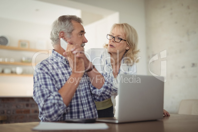 Senior man holding call while talking to his senior woman