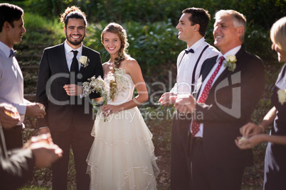 Portrait of bride and groom standing with guests