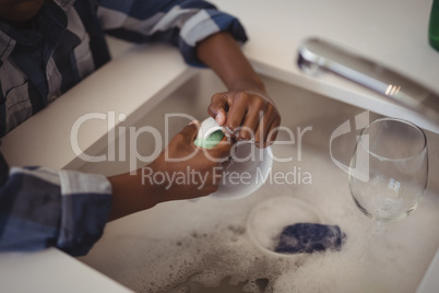 Boy washing cup in kitchen sink