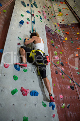 Woman practicing rock climbing in fitness studio