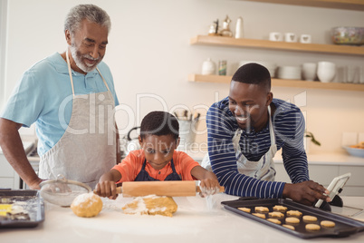 Boy preparing cookie dough with his father and grandfather in kitchen