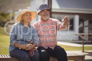 Senior couple pointing at view while sitting on bench