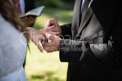 Groom putting engagement ring in woman finger