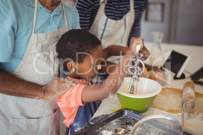 Boy learning to whisk the eggs while preparing cookies