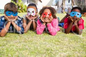 Children wearing masks lying on field in yard