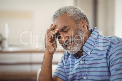 Tense senior man sitting in living room