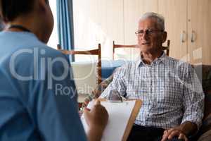 Man interacting with female doctor writing on paper in nursing home