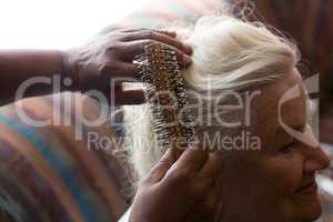 Cropped hands of doctor combing hair of female patient