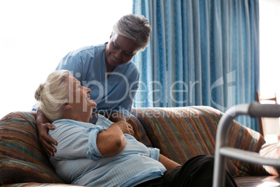 Nurse talking to female patient sitting on sofa