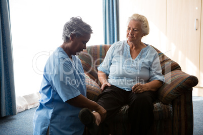 Nurse helping senior woman in stretching legs