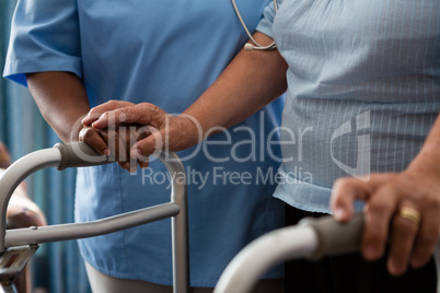 Nurse assisting senior patient in walking with walker at nursing home