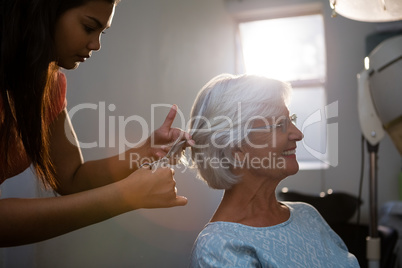 Hairsylist cutting hair of senior woman