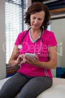 Physiotherapist using mobile phone on bed
