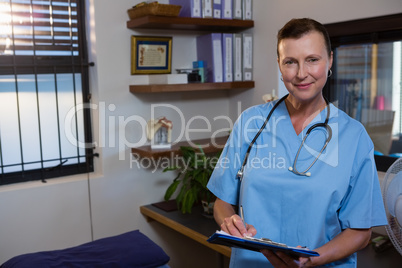 Female doctor writing on clipboard in hospital