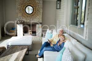 Smiling granddaughter and grandmother using digital tablet on sofa