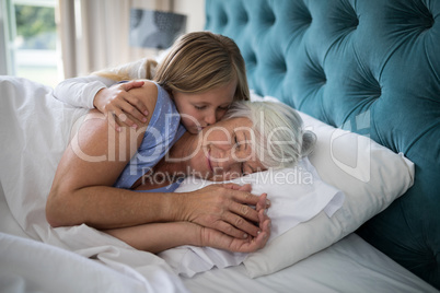Granddaughter kissing her grandmother on bed