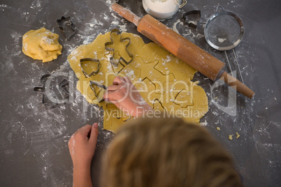 Cropped image of boy making shapes from cookie cutter