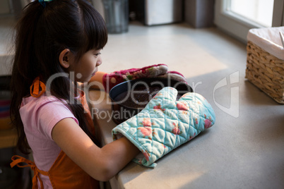 Girl with cake container at kitchen counter